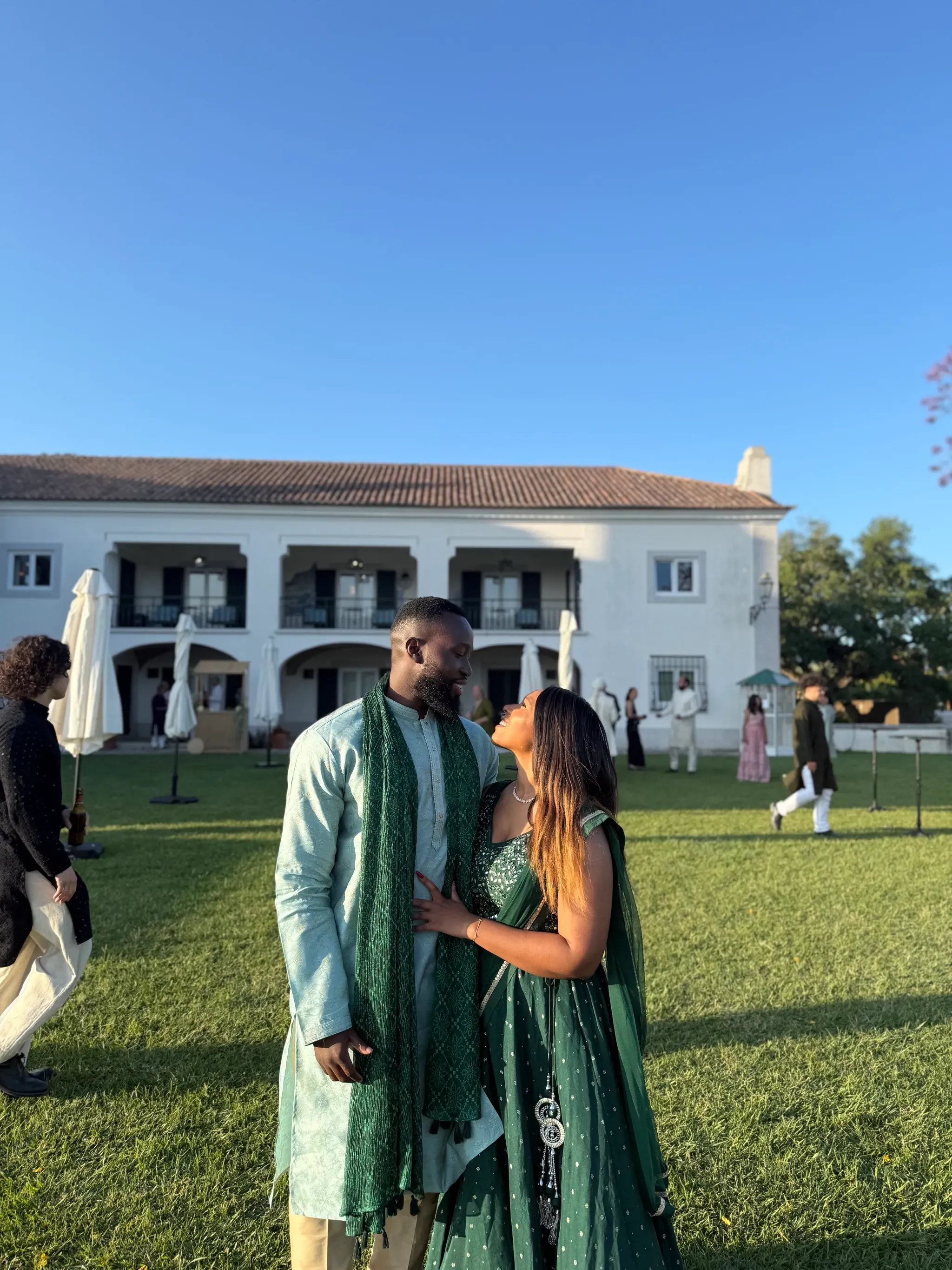Nuriel and Joshua on a lawn at golden hour, dressed in emerald and mint